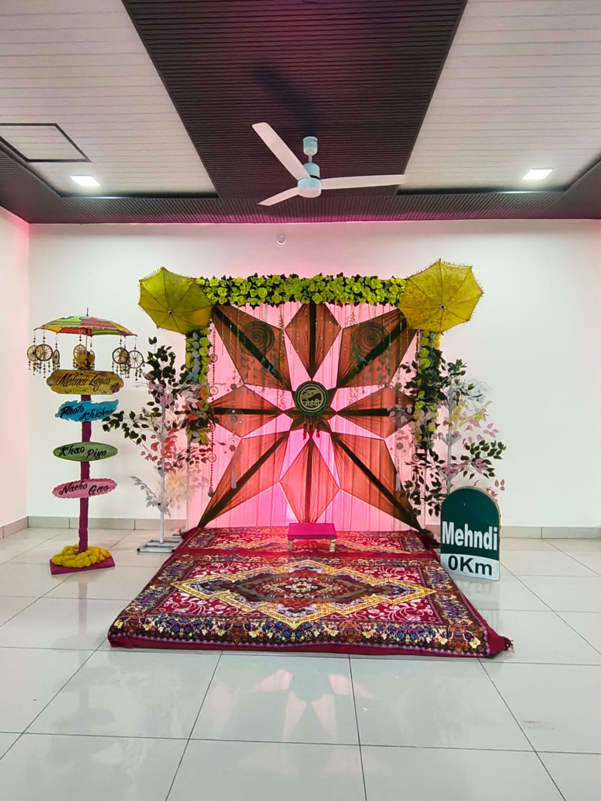 Mehndi celebration stage with floral backdrop and decorative umbrellas