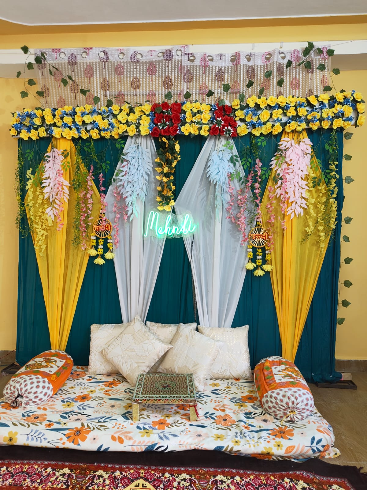 Mehndi floral decoration with yellow flowers and green and white drapes